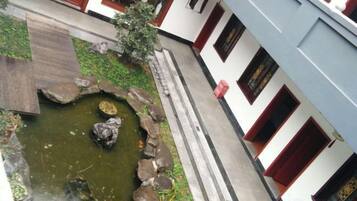 A courtyard with a small pond, stone pathway, and traditional architecture.