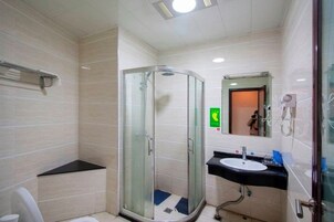 Un baño moderno con ducha envuelta en vidrio, un lavamanos y un inodoro.