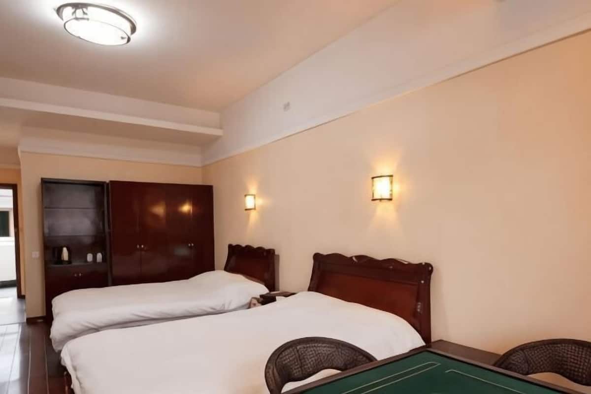 Quarto de hotel com duas camas, mesa de bilhar e guarda-roupa.