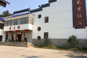 A building with a traditional architectural style, featuring a prominent entrance with a red awning and a sign above the door. - Maojia Hotel (Shaoshan)