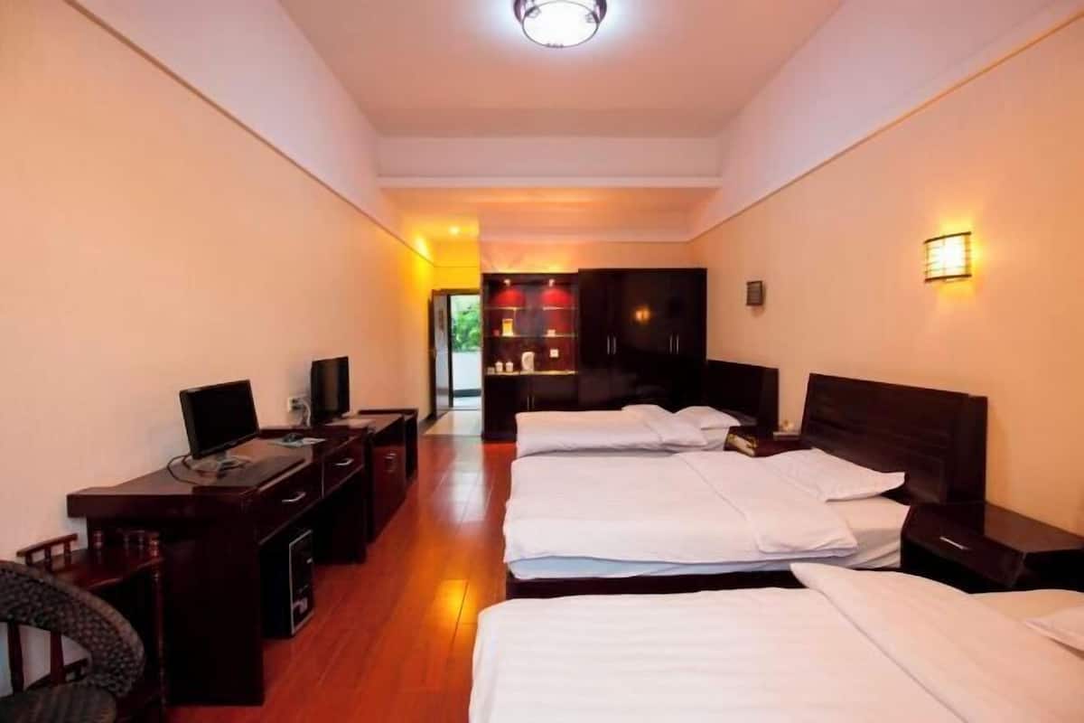 Quarto de hotel com duas camas, uma mesa de escritório com computador e uma televisão.