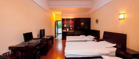A hotel room with two beds, a desk with a computer, and a TV.