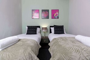 A twin room with two beds, a nightstand, a lamp, and three wall-mounted artworks.