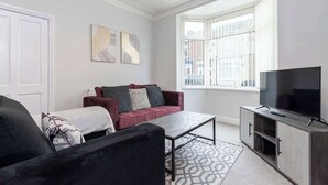 Un salon moderne avec un canapé, une table basse et un téléviseur posé sur un meuble.