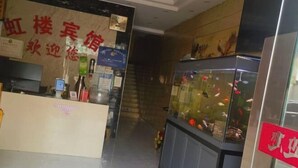 Área de recepção de hotel, com balcão, aquário e placa.