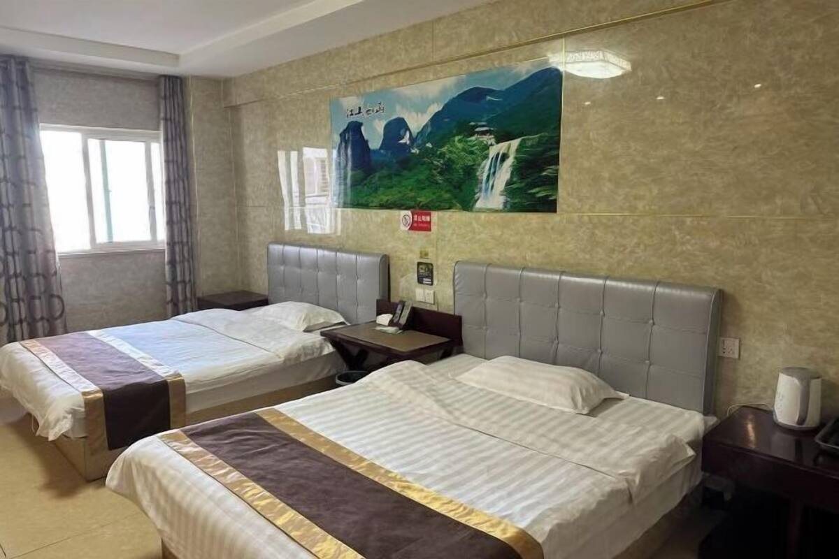 A hotel room with two beds, a large poster on the wall, and a window with curtains.
