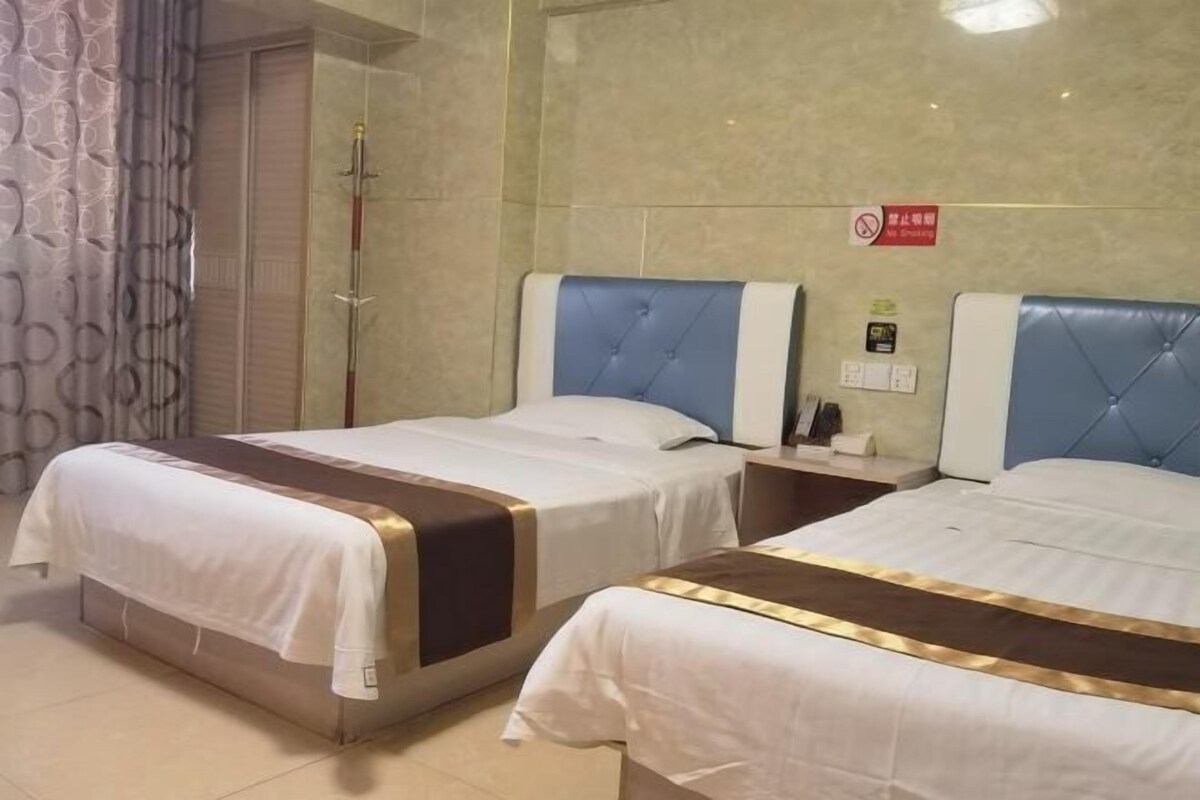 Quarto de hotel com duas camas, chuveiro e placa indicando que não é permitido fumar.