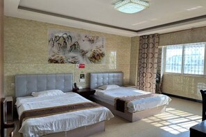 A hotel room with two beds, a large wall painting, a window with curtains, and a ceiling light fixture.