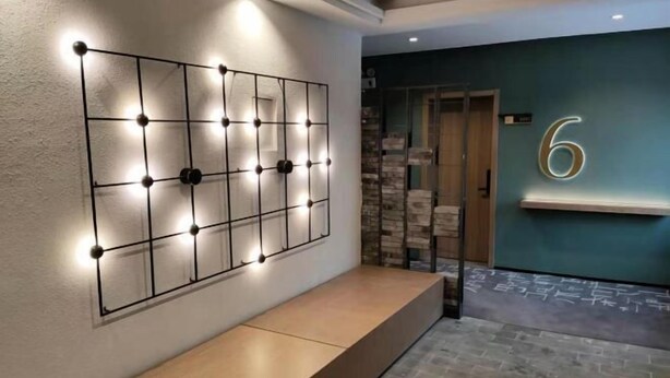 Un hall d’hôtel au design moderne, comprenant un luminaire fixé au mur et un panneau portant le chiffre « 6 ».