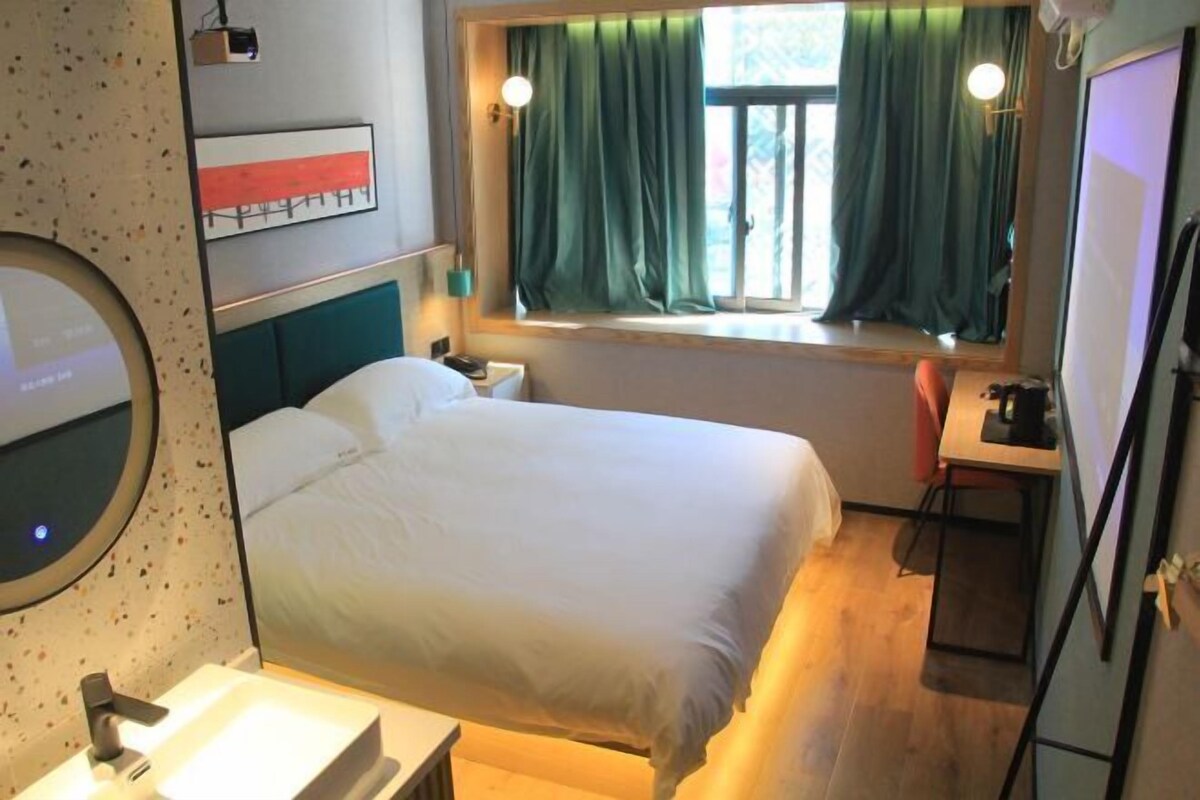 Une chambre d’hôtel avec un lit, une table de chevet et une fenêtre avec des rideaux.