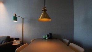 Une salle de conférence avec une longue table, quatre chaises, une lampe de bureau verte et un luminaire suspendu.