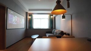 Une pièce moderne équipée d’un grand écran diffusant du contenu, d’un canapé, d’une table et d’une lampe suspendue.