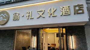 L’entrée d’un hôtel, avec une enseigne en caractères chinois, une porte en verre et un intérieur visible, où l’on aperçoit une salle à manger.