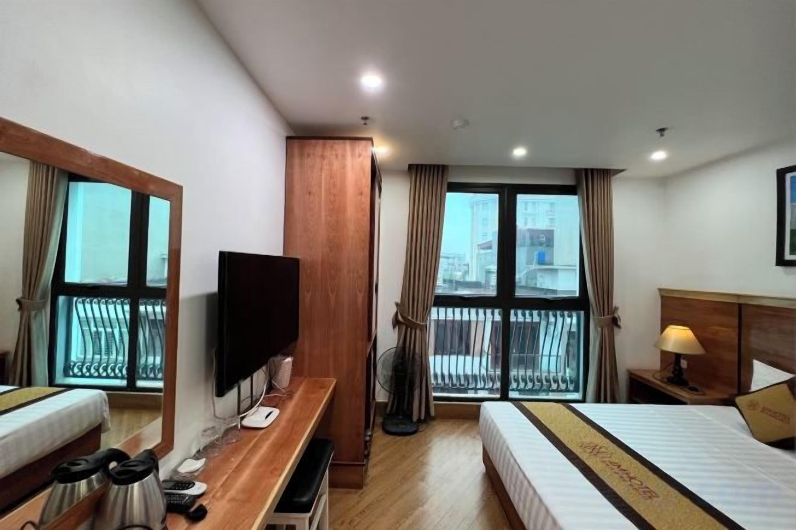 A hotel room with a bed, a desk, a television, and a balcony with a view.