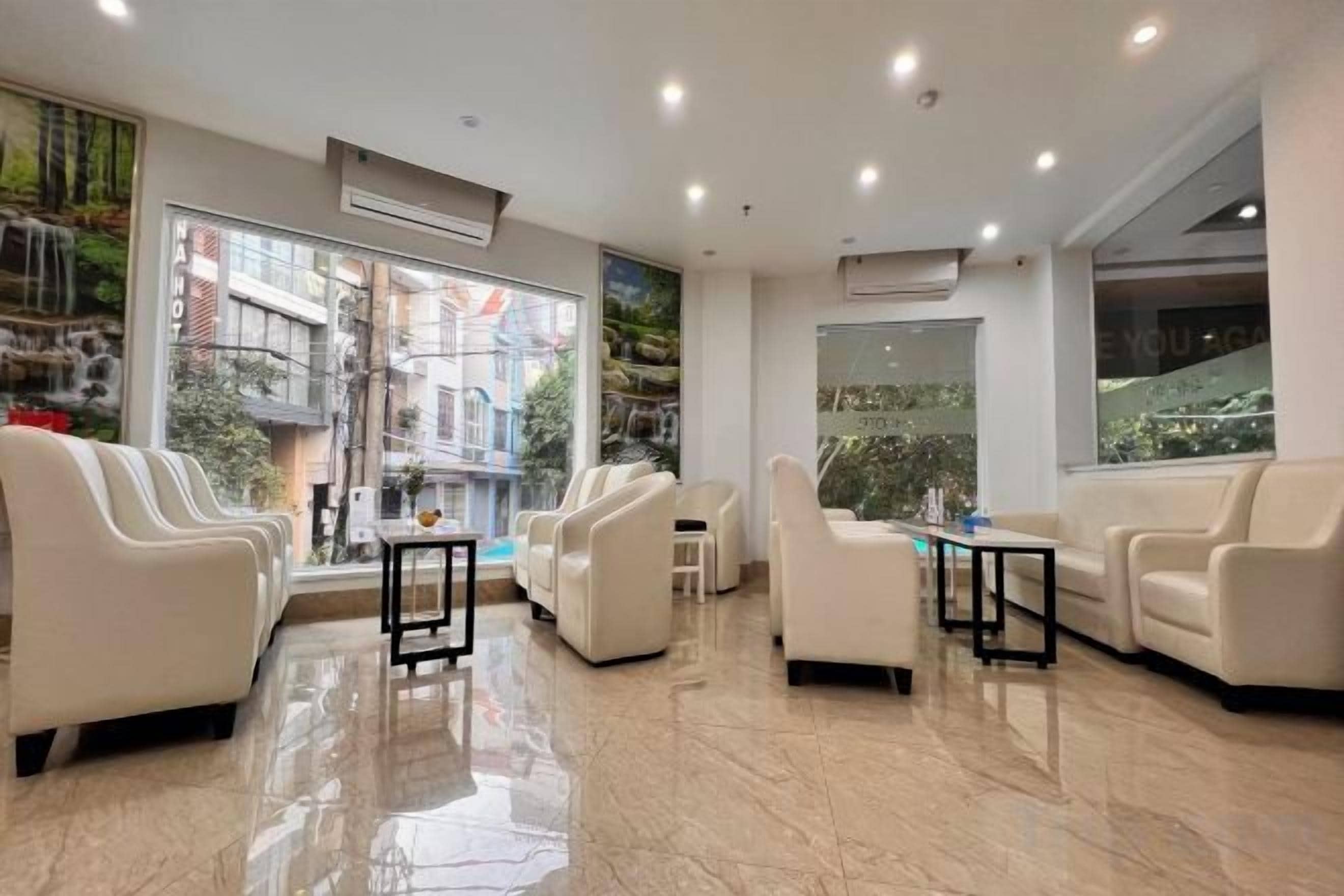 Un hall de hotel con áreas de descanso, una mesa de recepción y grandes ventanales que ofrecen vistas al exterior.
