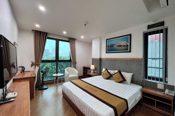 Una habitación de hotel con cama, escritorio, silla, televisor y ventana con vistas.
