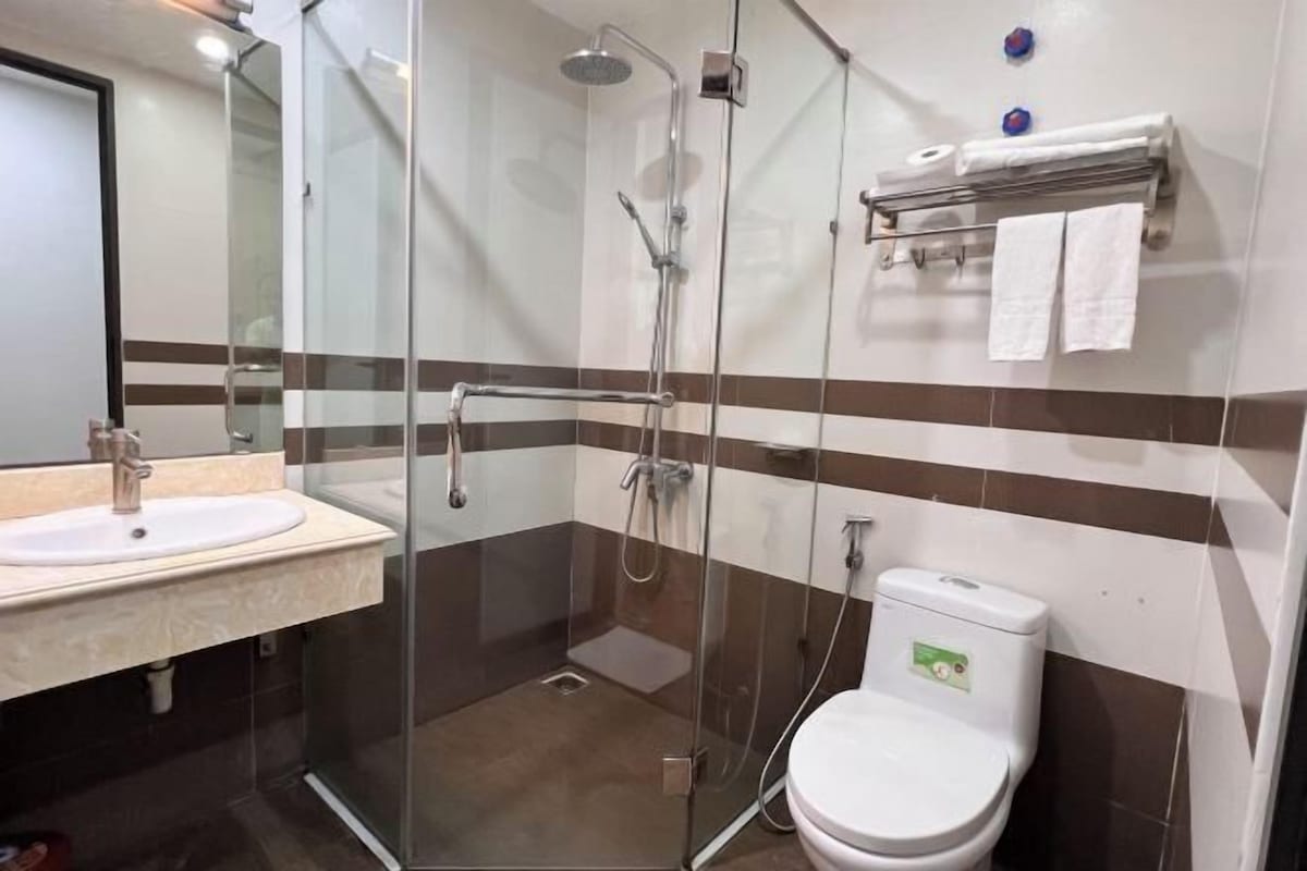 A bathroom with a glass-enclosed shower, a sink, and a toilet.