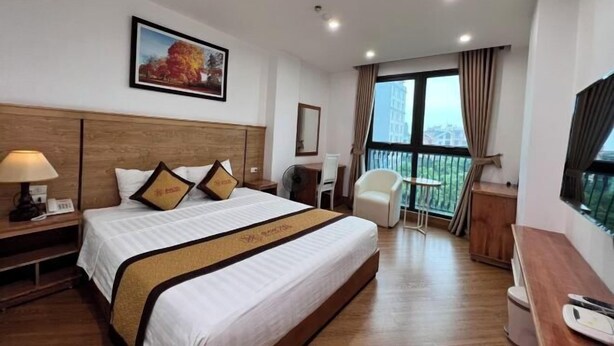 A hotel room with a large bed, a desk, a chair, and a balcony with a view. - Kezan Hotel 4m2 (Vo Cuong)