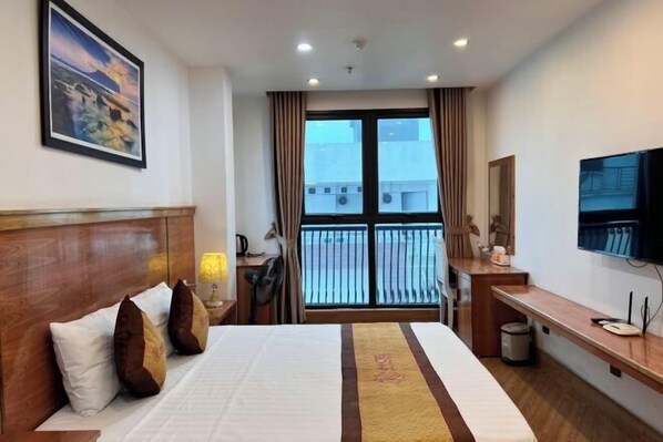 Una habitación de hotel con una cama, un escritorio, una silla, un televisor y una ventana con cortinas.