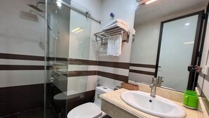 A bathroom with a glass-enclosed shower, a toilet, and a sink with a mirror above it. - Kezan Hotel 4m2 (Vo Cuong)