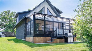 A modern house with a large glass extension, a wooden deck, and a barbecue area. - Riverside Cabin 5
Three season Riverside escape (Campbellford)