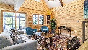 A cozy log cabin interior with a sofa, two armchairs, a coffee table, and a fireplace. - Riverside Cabin 5
Three season Riverside escape (Campbellford)