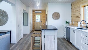 A modern kitchen with a central island, wooden flooring, and white cabinetry. - Riverside Cabin 5
Three season Riverside escape (Campbellford)