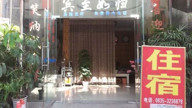 A hotel entrance with a glass door, a signboard with Chinese characters, and a red signboard advertising rooms for rent.