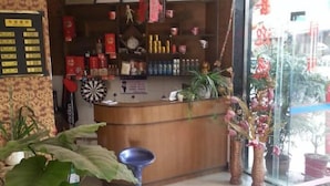 A reception area with a wooden counter, potted plants, and a dartboard.