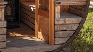 A wooden cabin with a circular design, featuring a built-in fireplace, a bench, and a door leading to an outdoor area. - Comfortable 3-Bedroom Vacation Rental: NUIKI Lodges (Montségur-sur-Lauzon)