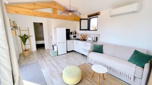 Une cuisine moderne avec des meubles blancs, un réfrigérateur et un four à micro-ondes. On y trouve également un coin repas avec un canapé blanc et une petite table ronde.