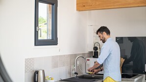 Une cuisine moderne équipée d’un four encastré, d’une bouilloire et d’une fenêtre située au-dessus de l’évier.