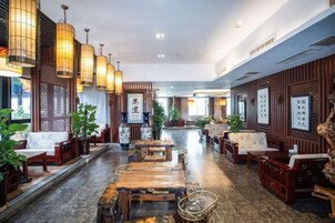Un vestíbulo de estilo tradicional con muebles de madera, faroles colgantes y plantas en macetas.