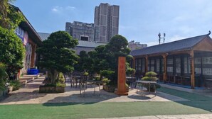 A courtyard with traditional architecture, a building with a tiled roof, and a tall structure in the background. - Jialong Hotel (Guangyuan High-speed Railway Station) (Guangyuan)