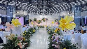 A venue with a central aisle, floral decorations, and a chandelier.