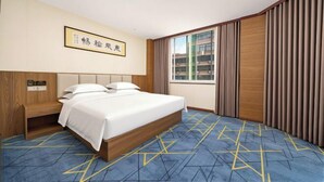 A hotel room with a bed, a wooden headboard, a nightstand, a window with curtains, and a wall-mounted sign. - Jialong Hotel (Guangyuan High-speed Railway Station) (Guangyuan)