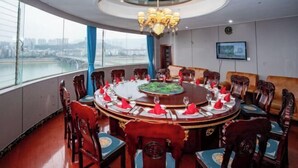 A round dining table with chairs, a chandelier, a television, and a view of a bridge. - Jialong Hotel (Guangyuan High-speed Railway Station) (Guangyuan)