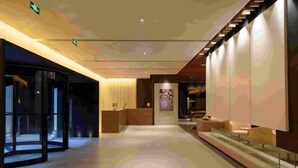 Eine großzügige Lobby mit Empfangsschalter, Sitzgelegenheiten und einer Treppe.