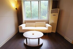 A room with a white sofa, a round table, and a window with curtains. - Jinjiang Inn Select (Lushan City)