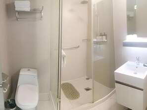 A bathroom with a toilet, a glass shower enclosure, and a sink.