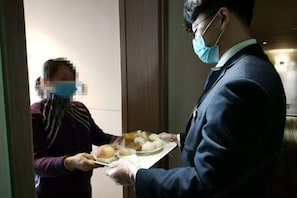 A person handing over a tray with food to another person in a hotel setting. - Jinjiang Inn Select (Lushan City)