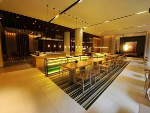 A modern interior with a central bar area, seating arrangements, and a large artwork on the wall. - Jinjiang Inn Select (Lushan City)