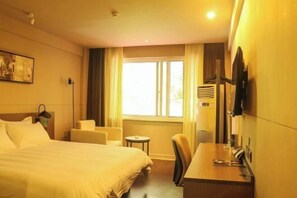 A hotel room with a bed, a desk, a chair, a small table, and a window with curtains. - Jinjiang Inn Select (Lushan City)