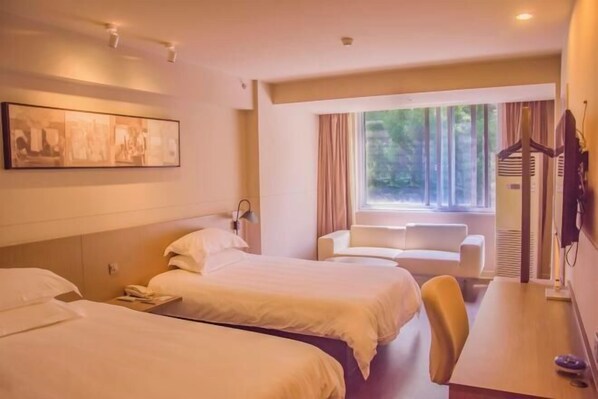 A hotel room with two beds, a desk, a chair, a window with curtains, and a wall-mounted TV. - Jinjiang Inn Select (Lushan City)