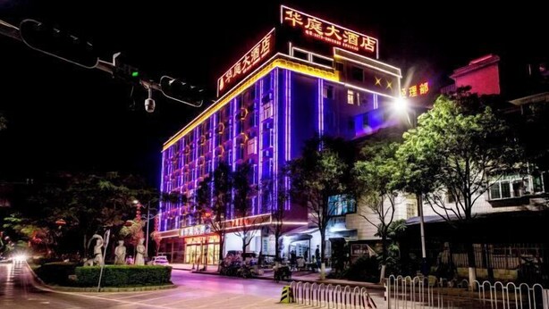 A hotel with a prominent sign, multiple floors, and a well-lit facade. - Huating Hotel (Mojiang)