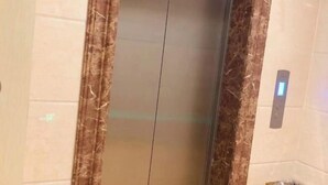 An elevator with a marble wall and a digital display. - Huating Hotel (Mojiang)