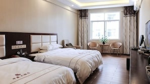 A hotel room with two beds, a desk, a chair, a TV, and a window with curtains. - Huating Hotel (Mojiang)