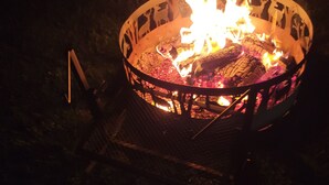 A metal fire pit with a decorative metal rim and a metal stand. - Pondside Campground (Meadville)