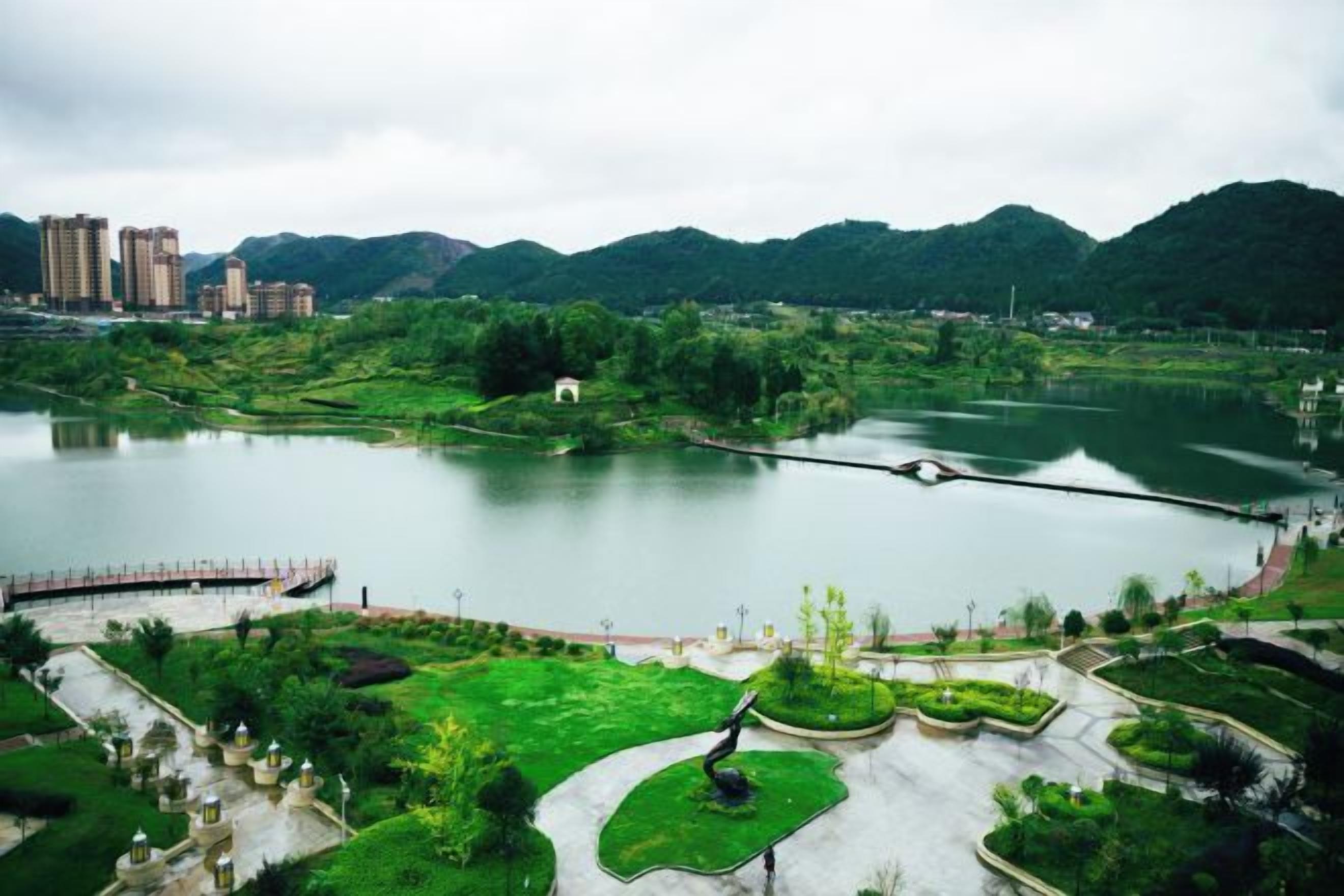 A park with a lake, pathways, and greenery.