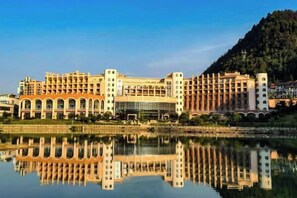 Un hotel grande con varios pisos, un patio central y un reflejo en el agua.